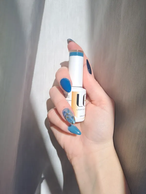 Blue gel nails holding a bottle of Bluesky gel polish
